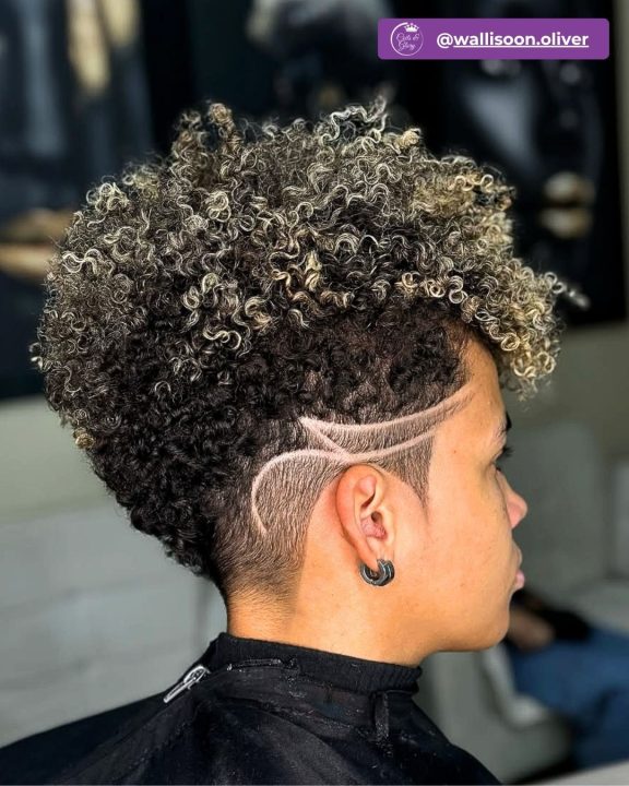 Modern ash blonde frosted taper cut with custom curved razor line design hair art on faded sides.