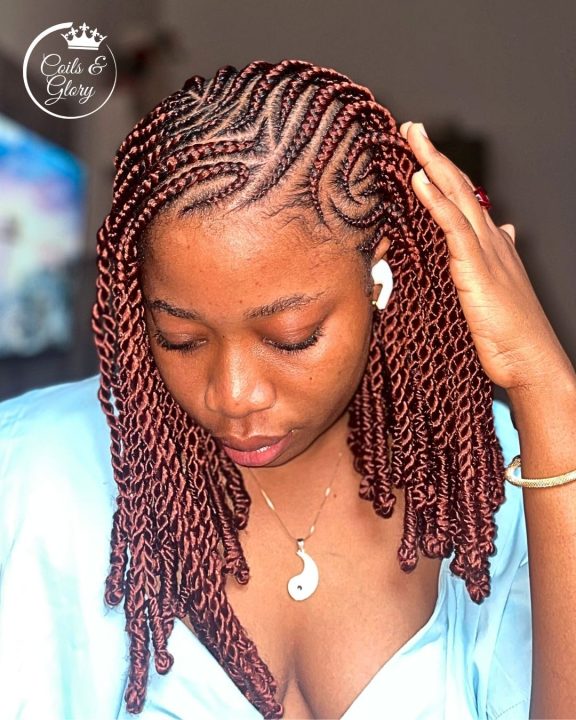 Auburn-colored side-swept Senegalese twists styled in a short bob with Bantu knots at the ends.
