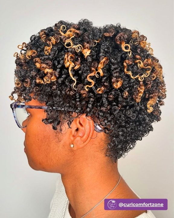Dark chocolate curly pixie taper featuring warm honey blonde accents.