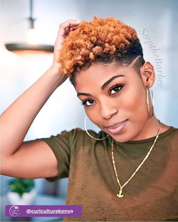 Ginger coiled taper cut women's haircut with custom razor line hair design on faded sides.