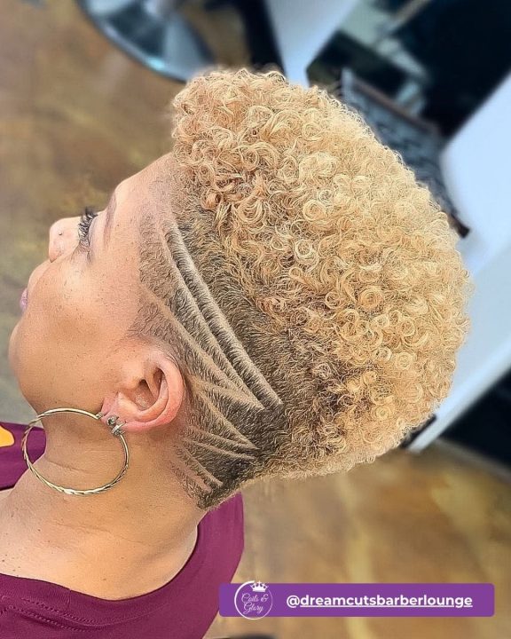 Golden blonde ringlet afro taper for women featuring a precise shaved geometric hair art design.