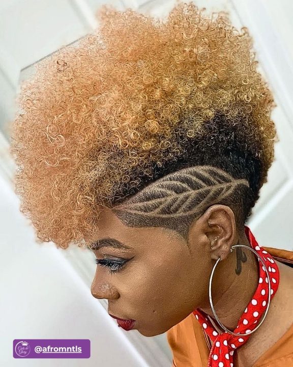 Honey blonde coiled frohawk women's haircut with custom leaf pattern hair art design on tapered sides.