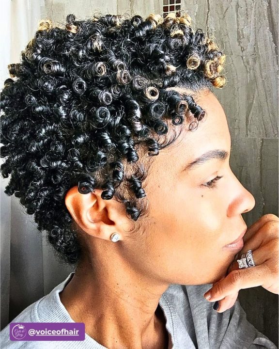 Jet black tight ringlet pixie afro cut for women featuring blonde tip accents.