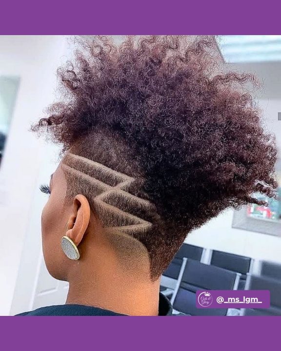 Mahogany coiled frohawk women's haircut with geometric razor line art on tapered sides.