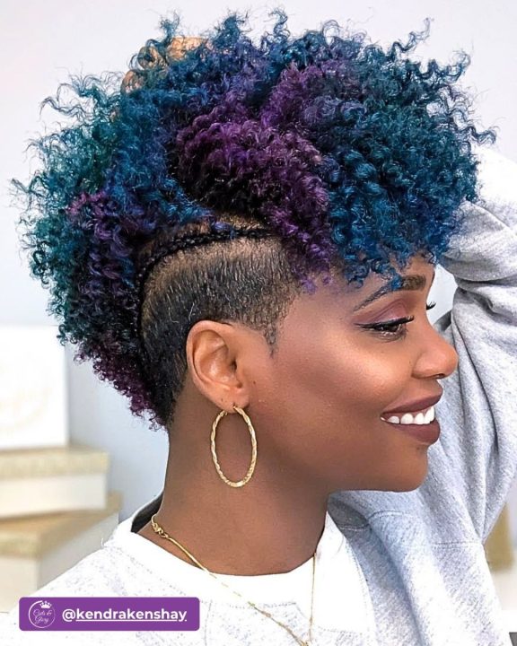 Vibrant teal and deep purple coiled frohawk with rich natural volume along the center, framed by clean tapered sides accented with a sleek side feed-in braid.